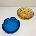 Dois cinzeiros de vidro na cor âmbar e azul. Dimensões: 14 cm diâmetro (maior peça).