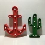 Dois letreiros luminosos no formato de âncora e cacto movido à pilha. Funcionando. Dimensões: 30 cm (maior peça).