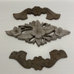 Lote com três florões, sendo dois de madeira e um de resina. Sinais de desgastes e um exemplar com pequena parte faltando. Dimensões: 28 cm comprimento (maior peça).