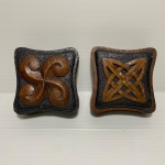 Dois pesos de madeira da década de 40, decorados com desenhos entalhados. Dimensões: 10 cm x 10 cm x 5 cm.