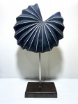 Escultura aspiral em metal na cor azul indico, com linhas brancas, no formato assimétrico semelhante a uma concha do mar. Dimensões: 29 cm.