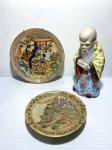 Lote com dois pratos de parede pintados à mão e estatueta de monge com restauro, ambos de origem oriental. Dimensões: 21 cm (maior prato)