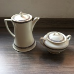 Conjunto com bule e açucareiro em faiança , decorado com faixa azul e amarelo com motivo vegetalista. Presença de bicado no açucareiro e no bule. Dimensões: 23 cm a maior peça.