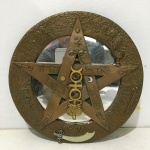 Placa circular com figura de pentagrama em resina, fundo espelhado e inscrições. Dimensões: 26 cm.