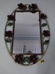 Belo espelho com moldura em fer forgé patinado, trabalhado com vazados, volutas, folhagens e flores em relevo. Med. total 69x48 cm.