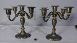 Par de candelabros para três velas em metal espessurado a prata com detalhes dourados. Hastes articuladas.  Medindo 20x23 cm.