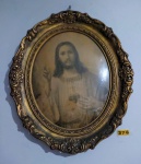 Antiga gravura do Sagrado Coração de Jesus com moldura oval em madeira trabalhada e patinada de dourado, vidro côncavo início do século xx, medindo 68x58cm.
