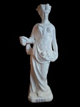 Escultura de faiança branca esmaltada, moldada na representação simbólica da estação do ano Outono em figuração feminina com frutos e cacho de uvas. Med. 80x23x17 cm. Fio de cabelo.