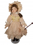 Colecionismo -Antiga boneca com mãos e rosto porcelana, pedestal em metal, com trajes típicos. Apresenta rosto rachado Med. 40cm.