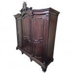 Robusto guarda roupa em Jacarandá, estilo Luis XV, com florão central, composto por três portas, 4 gavetas centrais, cabideiro e esteira para calças, acompanha uma chave, marcas do tempo e arranhado próximo a fechadura, Med. Alt. 225, 207x62cm