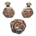 Terno de peças em porcelana anos 50 com rica policromia, realçada a ouro, sendo um despojador e dois perfumeiros. Med. Alt. 5cm, diam. 10cm e 13cm, 6x10cm.