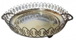 Centro de mesa com bordas vazadas e trabalhadas com 3 pés de sustentação e Alça nas laterais. Medidas: Altura 7cm e Diâmetro 23cm.