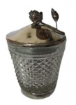 Manteigueira com base e tampa em metal espessurado a prata com detalhe de uma rosa e vidro estilo bico de jaca. Medidas: Altura 15cm Diâmetro 9cm.