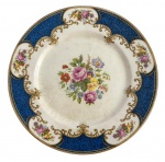 ENGLAND  STAFFORDSHIRE - Prato para coleção em porcelana inglesa do séc. XIX., fartamente adornado com magníficos ramalhetes de flores policromados e volutas em vibrante ouro sobre borda azul. Possui registro da manufatura. Mede 25,5cm.