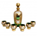 VENEZA - Magnifico serviço para licor em cristal verde veneziano fartamente adornado à mão com motivo floral em relevo sobre fundo em vibrante ouro. Composto de garrafa com tampa no formato bola e seus seis cálices. Medida do maior 23cm.