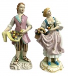 EUROPA - Par de graciosas esculturas em biscuits europeu representando casal de camponeses portando frutas em rica policromia. Uma com numeração na base. Mede 22cm altura.