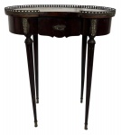 LUIS XVI - Mesa lateral em madeira acastanhada, formato oblonga, tampo guarnecido por galeria em bronze, pernas longas que sustentam gaveta central com puxador e apliques de metal, de estilo francês LUIS XVI. Meados 1900. Possui cachê. Mede 57 x 69cm altura.