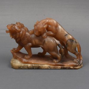 Escultura europeia de alabastro em tom de bege representando leão sendo atacado por um tigre. Med. 2