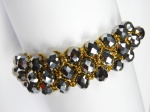 Pulseira de linha dourada com trama de cristais negros.  Tamanho regulado por ajuste da linha