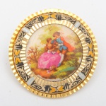 Belíssimo brocha ao gosto ouro de Toledo, bordas ricamente  ornadas e medalhão central de porcelana com pintura de cena romântica. 3,8 cm diam