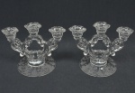 Par de candelabros em demi cristal americano incolor com 3 braços sinuosos e ornamentados com volutas estilizadas. Base circular plana com delicados entalhes florais no padrão fosco 20x16 cm