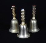 Trio de sinos em metal dourado, adornado com pedrarias, sendo dois deles com as pedras vermelhas e um com as pedras brancas e verdes. Marcas do tempo. 8,5x4 cm.