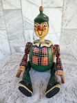 PINÓQUIO - escultura em madeira representando o famoso  personagem . Trata-se de um  pinóquio sentado com as pernas estendidas e os braços articulados . Mede 32 cm .