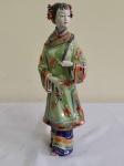 Figura feminina em cerâmica e biscui esmaltada e policromada representando asiática .Apresenta assinatura e marca de procedência .Faltam dois dedinhos. Altura 29 cm.