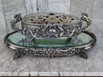 Magnífico CENTRO DE MESA -  FLOREIRA medindo 42 x 21 x 11 cm em PRATA PORTUGUESA com aconcheados e ricos trabalhos integrando presentoir com espelho bisotado  47  x 32 x 6  cm. Peso da prata  floreira - 1640 gramas , tampa da floreira 350 gramas e presentoir 1200 gramas descontado  o espelho e o revestimento interno . ( só mesmo a prata ). Total Prata pura 3190 gramas. Peça se apresenta em ótimo estado e com contraste em todas suas peças.