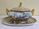 Terrina com presentoir em porcelana SMITH  . Apresenta decoração de cenas idílicas e campestres com rica policromia e ouro.  Pega e alças laterais totalmente cobertas com ouro. Medida do presentoir 37 x 25 cm ,e terrina 30 x 24 x 23 cm.