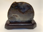Placa de Ágata Polida com Base em Madeira  Peça Decorativa NaturalPeça única e elegante, composta por uma fatia de ágata natural com veios em tons de marrom, cinza e branco, montada sobre base de madeira escura e brilhante. O polimento realça os detalhes internos da pedra, oferecendo uma aparência orgânica e sofisticada. Material: ágata natural polida Base em madeira com acabamento refinado Ideal para decoração de interiores, ambientes zen ou coleções de minerais