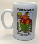 Caneca Oficial  6ª Oktoberfest Blumenau  Outubro de 1989Celebre uma das maiores festas alemãs do Brasil com esta caneca vintage da 6ª edição da Oktoberfest de Blumenau, realizada entre 6 e 22 de outubro de 1989. Produzida em cerâmica branca com ilustração colorida, a peça mostra um simpático personagem em trajes típicos bávaros, segurando um caneco espumante de chope  símbolo da alegria e tradição do evento.