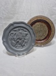 Lote de 2 pratos decorativos, sendo um em estanho e um em madeira. Medindo o maior 25,5cm de diâmetro.