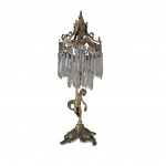 Luminária de mesa em bronze com franja de gotas de cristal arte superior em braços recurvos , topo em formato de coroa com laçarotes e topo em pinha, haste representando anjo encimado em base de quatro pés, Alt. 55 cm.