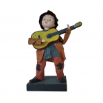 Escultório em papier machê representando menino tocando violão, rosto em cerâmica apoiado em base de madeira, Alt, 26, base: 12 x 9 cm.