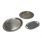 Três bandejas em inox diversas, juma delas com galeria adornada com acantos em alto relevo, Diam. 30, 31 e  23 x 14 cm.