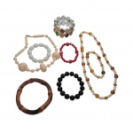 Seis pulseiras e dois colares femininos diversos, a pulseira de pedras multicoloridas sobre fundo prateado apresenta manchas pretas na parte interna.
