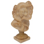 Escultura em alabastro bege, representando busto feminino com grande echarpe rendada sobre a cabeça. Haste curta com base circular, apoiada em peanha quadrangular. 38 x 22 cm. Pequenos bicados.