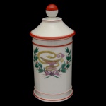 Pote de farmácia de louca branca. Apresenta frisos terracota e decoração verde. 26 x 12 cm.