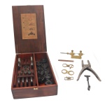 STANDARD UNBREAKABLE WATCH CRYSTALS - Conjunto profissional americano com instrumentos e ferramentas para encaixar lentes circulares. Acondicionado em caixa retangular em madeira nobre. Instruções impressas no verso da tampa. 8 x 36 x 25 cm (caixa). Sinais de uso e do tempo.