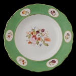 SERVIÇO DUQUE DE CAXIAS - Raríssimo prato raso de porcelana francesa pertencente ao Serviço de Duque de Caxias. Rica decoração em reservas, com arranjos florais policromados e realces a ouro sobre fundo verde. Brasão de Armas do Império ao centro. No verso marcas da manufatura Ch. Pillivuyt. Paris. Séc. XIX. 26 cm. Peça similar reproduzida à pág. 209 no Livro Louça da Aristocracia do Brasil, por Jenny Dreyfus. Fios de cabelo.