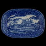 Travessa ovalada em louça inglesa, decorada em azul. Apresenta larga margem ornada por frisos geométricos, centralizando paisagem marinha com palácio. Marca da manufatura no verso. 28 x 20 cm.
