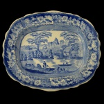 Travessa em louça inglesa de formato oval e borda recortada. Apresenta decoração em azul sobre branca com riacho, ponte, castelo e personagens. Sem marca. 30 x 26 cm.