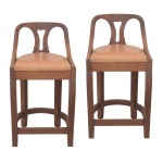 Par de bancos altos em madeira lisa. Encostos retos e vazados com montantes lisos. Assentos forrados em couro marrom claro. Saias apoiadas em pernas retilíneas, reunidas às bases por traves, sendo as detrás em meia lua. 80 x 42 x 37 cm.