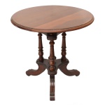 Mesa de apresentação com tampo circular, apoiada em colunas laterais torneadas e realçadas por anelados. Pequeno plateau inferior de formato triangular e laterais arqueadas, sustentado por pernas recurvas e filetadas, rematadas por pés lisos. 60 x 65 cm.