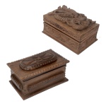 Conjunto de 2 caixas retangulares de mesa, em madeira profusamente esculpida, ornadas por frisos estilizados e geométricos. Tampas encimadas respectivamente por medalhão oval lobulado e figura de dragão encaracolado. Leve rachadura em uma caixa. 9 x 20 x 13 cm e 11 x 25 x 15 cm.