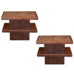 Par de mesas laterais construída com 2 plateaux quadrangulares superpostos, bordados por frisos lisos e reunidos por par de montantes retangulares. Base repetindo formato e tamanho dos referidos montantes. Tampo em cortiça prensada. 52 x 68 x 40 cm.