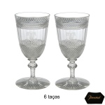BACCARAT  Conjunto de 6 copos de pé alto em cristal francês. Bojos cônicos, lapidados e ornados por barras com finas treliças em bico de jaca. Largas faixas centrais lisas, realçadas por monogramas gravados. Hastes aneladas, apoiadas em bases circulares lavradas.