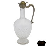 BACCARAT - Jarra francesa para vinho em cristal com montagem em metal acobreado. Bojo com iniciais entrelaçadas, no formato de balaústre, lapidado e ornado com treliças e feixes apoiado em base circular. Alça em S e bico curto. Marca da Cristalerie Baccarat. 26 cm.