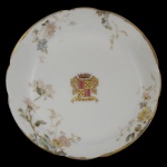 BARÃO DE PORTO FELIZ  Covilhete em porcelana europeia policromada, pertencente ao Serviço do primeiro e único Barão de Porto Feliz (Cândido José de Campos Ferraz - Campinas, 1830 - Rio Claro, 1880). Apresenta borda recortada e filetada em dourado. decorada em alto relevo com ramos de flores, e ao centro o brasão com armas. França. Século XIX. Marca da manufatura Limoges Haviland ao fundo. 15 cm. Fazendeiro e político brasileiro, líder do Partido Conservador na região de Limeira, São Paulo, e fundador da colônia agrícola de Boa Vista.